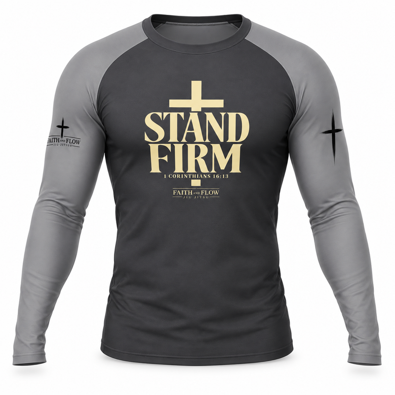 A long-sleeve raglan t-shirt in dark gray and medium gray, featuring a gold graphic on the chest that reads 'STAND FIRM' with a cross above it, and 'FAITH - FLOW' printed on the sleeve.